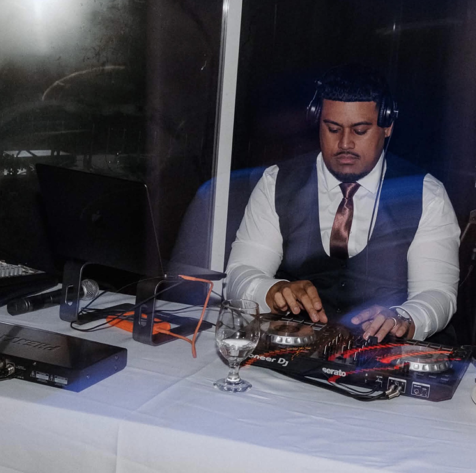 DJ Songz in a suit and tie mixing on Pioneer decks at a wedding reception