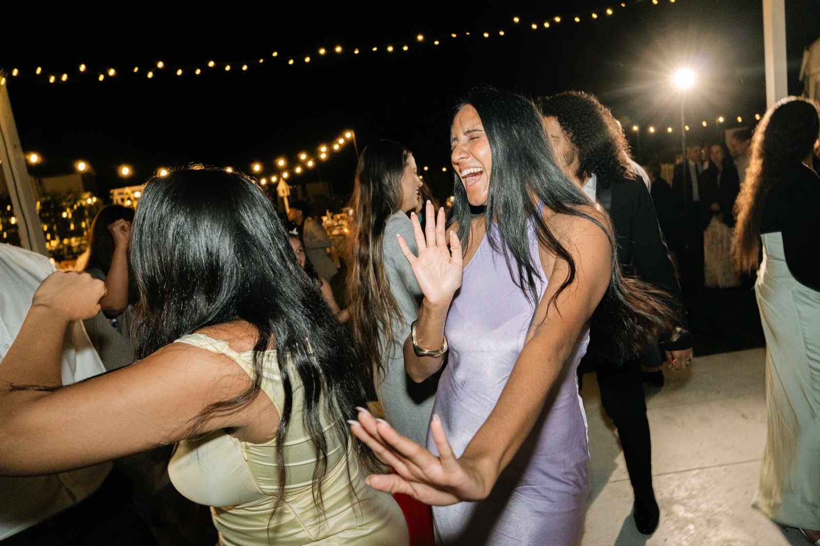 Guests laughing on the dance floor under festoon lights